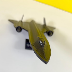 Puede incluir: Un modelo de avión SR-71 Blackbird de plástico verde y negro. El modelo es detallado.