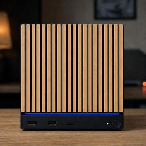 May include: A square electronic device featuring a front panel with vertical light brown wooden slats. A thin horizontal blue LED light strip sits below the slats. The black base includes two USB ports, a small indicator light, and a circular button.