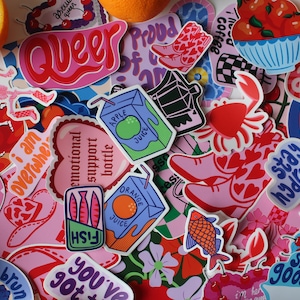 Puede incluir: Una colecci&oacute;n de pegatinas coloridas con varios dise&ntilde;os, que incluyen un esqueleto, un coraz&oacute;n con el texto "botella de apoyo emocional", un pez en una lata, un cangrejo, una caja de jugo, un par de zapatos rosas, una rama de cerezas y la palabra "queer" en letras rosas y rojas.