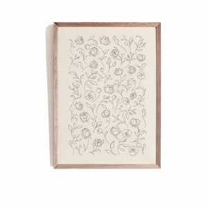 May include: A framed print with a black and white line drawing of a floral pattern. The print features a variety of flowers and leaves, all drawn in a simple, elegant style.