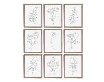 May include: Nine framed botanical art prints. Each print features a minimalist line drawing of a flower or foliage in black against a white background. The frames are a light brown color, and the arrangement is in a three-by-three grid.