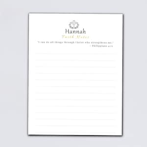 May include: A white notepad with the name "Hannah" and the words "Faith Notes" printed in a decorative font. The notepad has lined pages and a quote from Philippians 4:13. A succulent plant and pens are in the background.