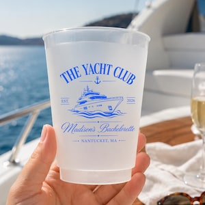 May include: A frosted plastic cup featuring blue text and a yacht graphic. The text reads THE YACHT CLUB, EST. 2026, Madison's Bachelorette, and NANTUCKET, MA. The design includes a small anchor icon above the yacht and decorative lines.