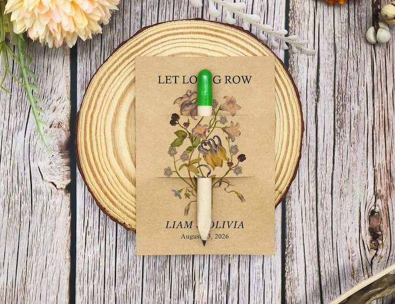 May include: A seed packet with the text "LET LOVE GROW" and the names "LIAM OLIVIA" and the date "August 3, 2026". The packet features a floral design and a green and white pencil. The packet is on a wooden slice.