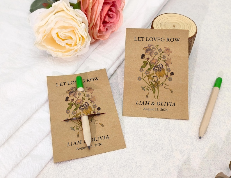 May include: Two kraft paper seed packets with floral illustrations and the text "LET LOVE GROW" and "LIAM & OLIVIA August 23, 2026". A pen with a green tip is inserted into one packet. Roses and a wood slice are in the background.