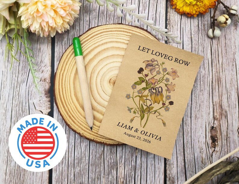 May include: A seed packet with the text "LET LOVE GROW" and the names "Liam & Olivia" with a date. The packet features a floral illustration and rests on a wooden slice with a green-tipped pencil. A "MADE IN USA" sticker is also visible.