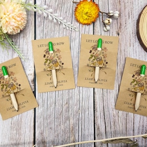 May include: Four kraft paper cards with pencils, featuring floral illustrations and the text "LET LONG ROW". Each card has the names "LIAM & OLIVIA" and the date "August 23, 2026". The pencils have green tops.
