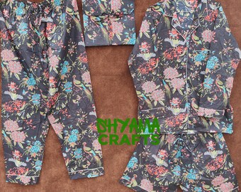 May include: A black pajama set with a floral and bird pattern. The set includes long pants, a long-sleeved button-down shirt, and shorts. The floral design features red, blue, and pink flowers and birds. The edges of the pajamas are trimmed with white.