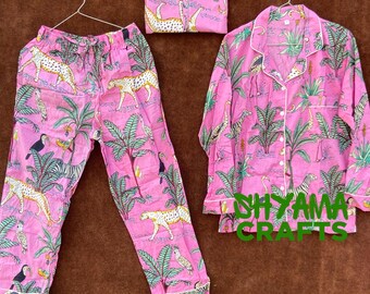 May include: Pink pajama set with a tropical print featuring toucans, leopards, and palm trees. The set includes a long-sleeved shirt with a button-up front and matching pants.