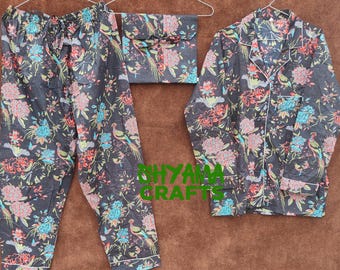 May include: A black pajama set with a floral and bird pattern. The set includes pants, a long-sleeved button-down shirt, and a matching pouch. The floral design features red, blue, and green accents.
