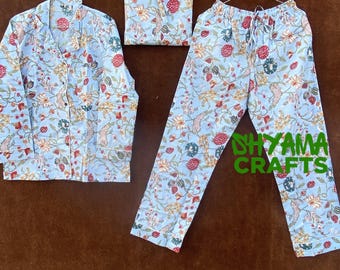 May include: A light blue pajama set with a floral print. The set includes a long-sleeved shirt with a button-up front and matching pants. The fabric has a delicate floral pattern in shades of red, yellow, and green.