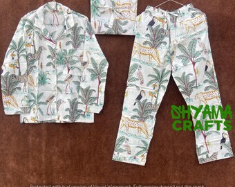 May include: White pajamas with a jungle print featuring palm trees, leopards, and birds. The top has a button-up collar and long sleeves. The pants have an elastic waistband.
