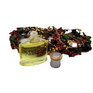 Puede incluir: Una botella de vidrio transparente de colonia Stetson Country con una tapa plateada y una corona de bayas decorativa. La botella est&aacute; llena de un l&iacute;quido amarillo. La corona presenta bayas rojas y amarillas con hojas verdes.