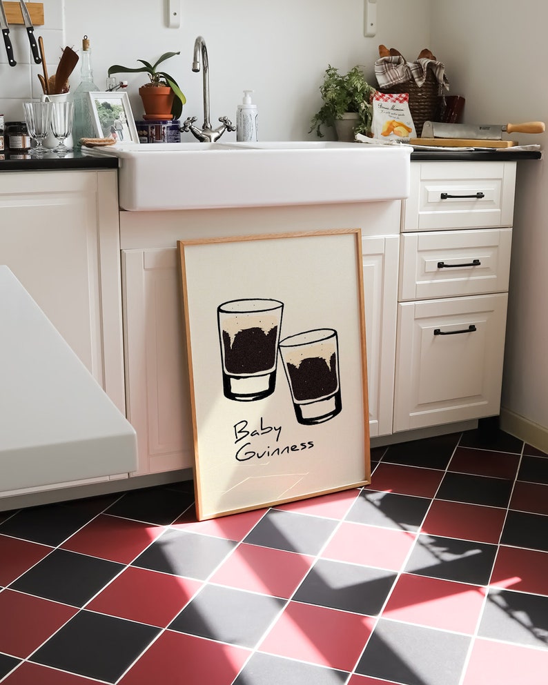 May include: A framed print with a white background and two black and white illustrations of glasses with the text "Baby Guinness" written below.