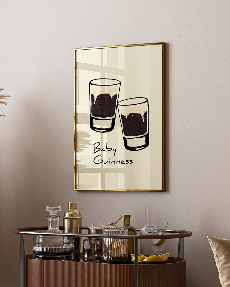 May include: A framed print with a minimalist illustration of two glasses of dark beer with the text "Baby Guinness" underneath.