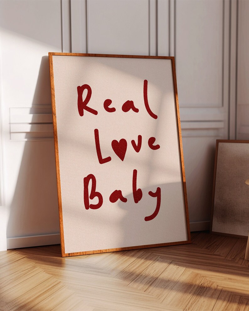 May include: A framed canvas print with the words "Real Love Baby" written in red cursive with a red heart in the word "Love".