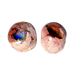 Puede incluir: Dos piedras redondas, de textura rugosa, con exterior marrón claro. Una piedra tiene una cavidad que revela una vibrante exhibición de iridiscencia azul, verde y púrpura. La otra piedra tiene una cavidad con un interior marrón dorado.