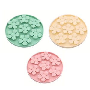 May include: Three silicone flower-shaped molds in pastel colours. One is mint green, another is pale yellow, and the third is light pink. Each mold has a circular base with seven flower-shaped indentations.