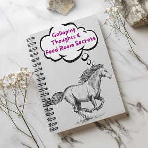 Puede incluir: Una libreta blanca de espiral con un dibujo en blanco y negro de un caballo corriendo. La libreta tiene un globo de pensamiento con el texto "Galloping Thoughts & Feed Room Secrets" en morado.