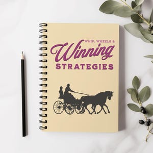 Puede incluir: Una libreta de espiral beige con el título "Whip, Wheels & Winning Strategies" en texto morado. La portada presenta una silueta negra de un carruaje tirado por un caballo.