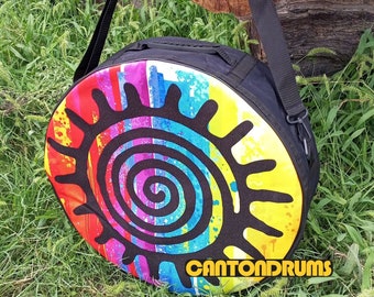 Può includere: Una borsa per batteria nera con un design a sole colorato e il testo "CANTONDrums" sul fondo. La borsa ha una tracolla nera regolabile.