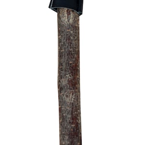 May include: A wooden stick with a black leather covering on the top. The leather is tied with a black string.