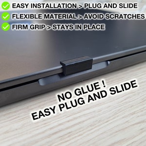 Könnte beinhalten: Nahaufnahme eines schwarzen Laptops mit einem schwarzen Plastikteil, das an der Seite befestigt ist. Der Text "NO GLUE! EASY PLUG AND SLIDE" ist in Weiß auf einer Holzoberfläche geschrieben.