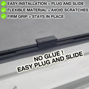 Puede incluir: Un soporte para portátil de plástico negro con una superficie texturizada. El soporte está diseñado para ser fácilmente enchufado y deslizado en su lugar en un portátil. El texto "NO GLUE! EASY PLUG AND SLIDE" está impreso en el soporte.