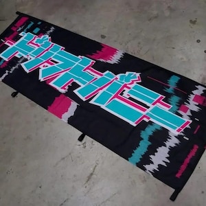 May include: A rectangular black fabric banner featuring large, stylized Japanese text in bright teal with white outlines. The design includes glitch-style graphic elements in vibrant pink, teal, and white, with black rods at the top and bottom edges.