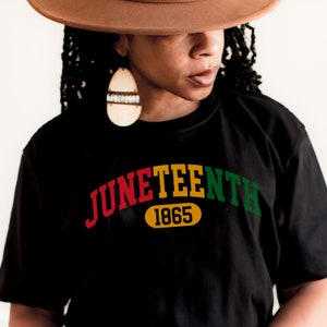 May include: Black t-shirt with a red, yellow, and green arc reading "Juneteenth 1865".