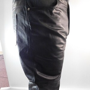 May include: Black leather pants with a classic five-pocket design. The pants have a straight leg cut and feature silver rivets and a small leather tag. The leather appears smooth and has a slight sheen. The pants are designed for a comfortable fit.