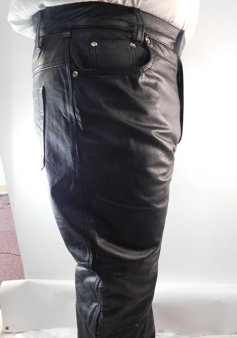 May include: Black leather pants with a classic five-pocket design. The pants have a straight leg cut and feature silver rivets and a small leather tag. The leather appears smooth and has a slight sheen. The pants are designed for a comfortable fit.