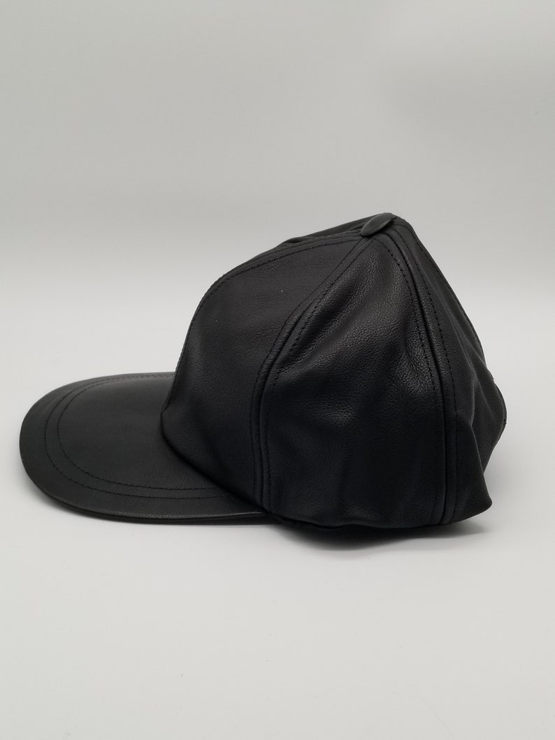 K&ouml;nnte beinhalten: Eine schwarze Baseballkappe aus Leder mit einem gebogenen Schirm. Die Kappe hat ein klassisches Design und ist aus hochwertigem Leder gefertigt.