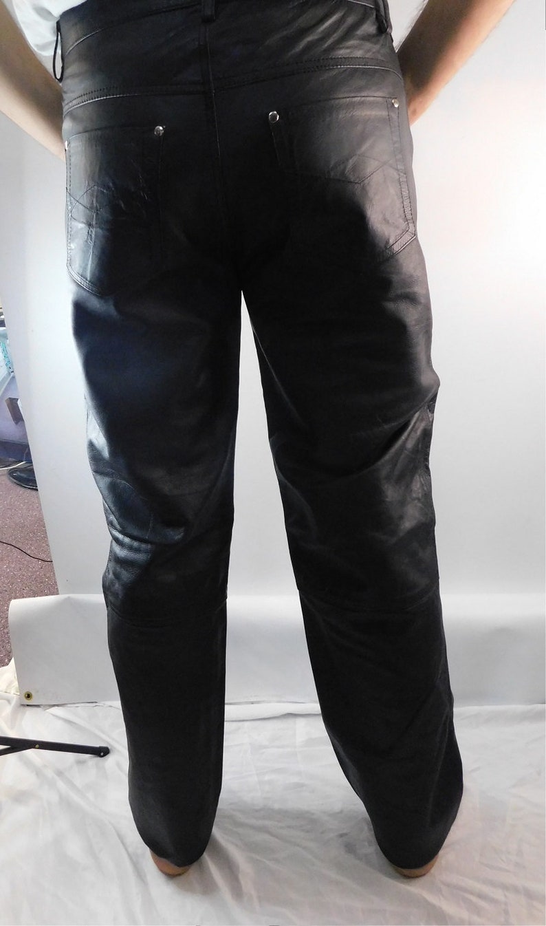 May include: Black leather pants with a classic five-pocket design. The pants have decorative stitching on the back pockets and silver-toned rivets. The leather appears to be soft and has a slight sheen.
