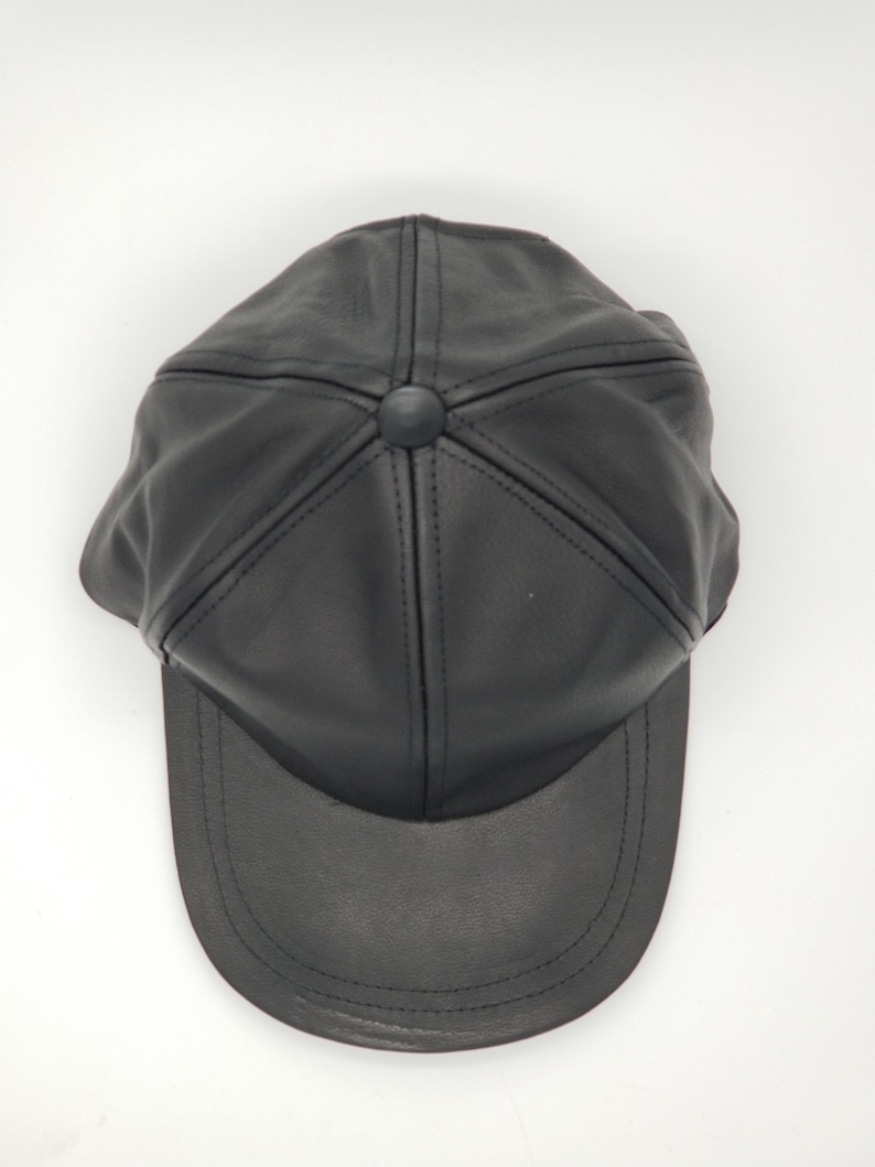 K&ouml;nnte beinhalten: Eine schwarze Leder-Baseballkappe mit einem gebogenen Schirm. Die Kappe hat ein klassisches Design mit einer sechsteiligen Konstruktion und einer gen&auml;hten Naht um den Schirm.