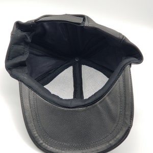 K&ouml;nnte beinhalten: Schwarze Baseballkappe aus Leder mit Mesh-Futter. Die Kappe hat einen gebogenen Schirm und einen schwarzen Riemen.