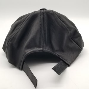 K&ouml;nnte beinhalten: Eine schwarze Baseballkappe aus Leder mit verstellbarem Riemen.