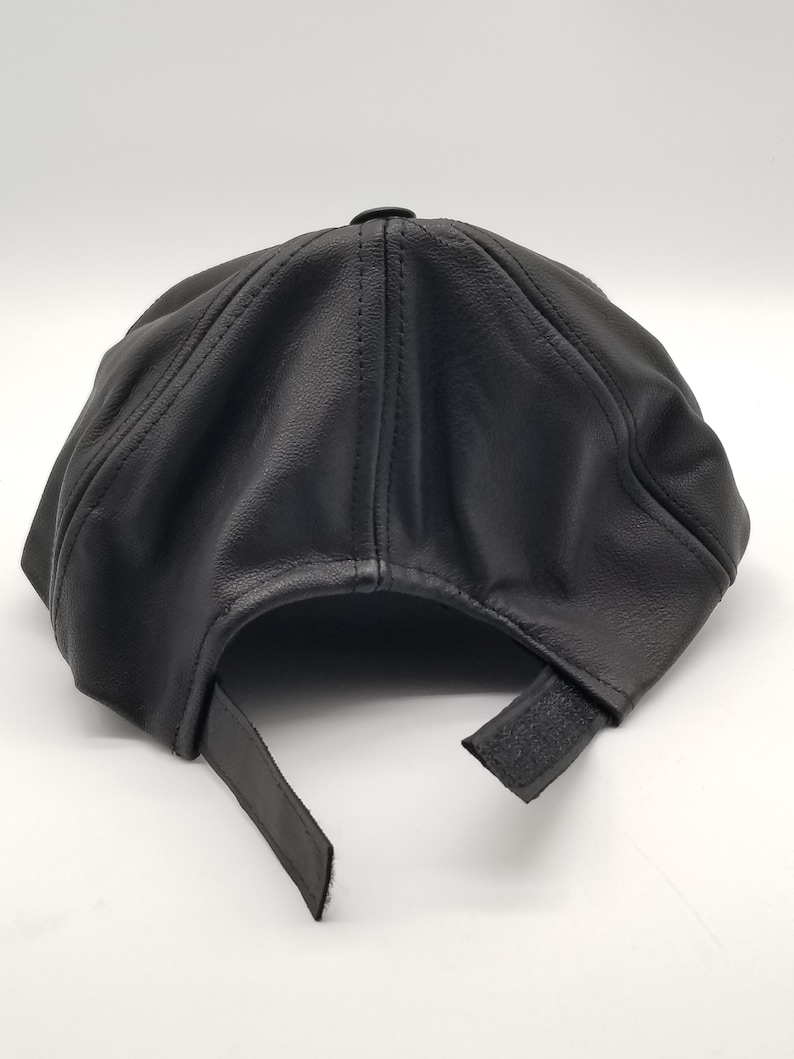 K&ouml;nnte beinhalten: Eine schwarze Baseballkappe aus Leder mit verstellbarem Riemen.