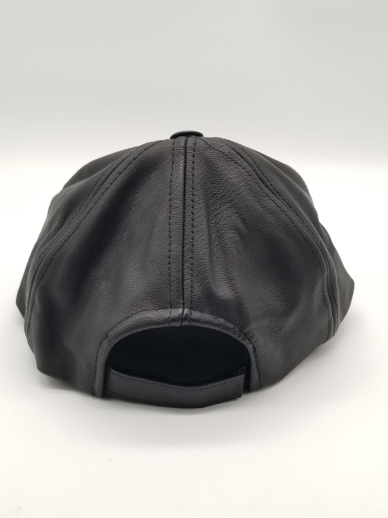 K&ouml;nnte beinhalten: Schwarze Baseballkappe aus Leder mit einem gebogenen Schirm und einem gesteppten Design. Die Kappe hat einen verstellbaren Riemen an der R&uuml;ckseite.