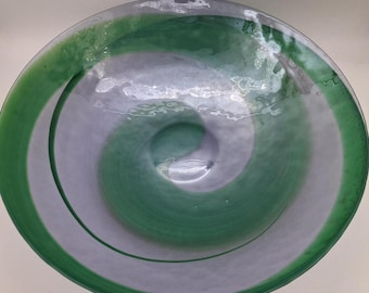 May include: A large, round glass bowl with a swirling green and white design. The bowl is made of clear glass with a textured surface.