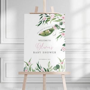 Peut inclure: Une pancarte de bienvenue pour une fête prénatale blanche avec des feuilles vertes et des fleurs roses. La pancarte indique "Two Peas in a Pod" et "Bienvenue à la fête prénatale d'Olivia" avec la date "9 septembre 2023".