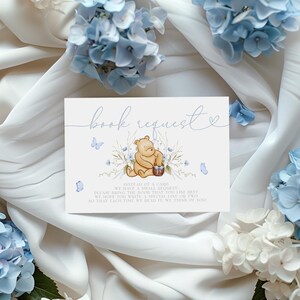 Pu&ograve; includere: Un biglietto di richiesta di libro a tema Winnie the Pooh con un design floreale blu e bianco. Il biglietto presenta un'illustrazione ad acquerello di Winnie the Pooh che tiene un cestino di miele. Il testo sul biglietto dice "richiesta di libro" e "Invece di un biglietto, quale piccolo lascito, porta il libro che ti piace di pi&ugrave;. Speriamo che tu scriva una riga o due speciali, in modo che ogni volta che lo leggiamo, pensiamo a te."