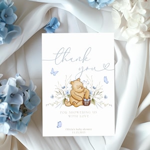 Pu&ograve; includere: Un biglietto di ringraziamento con un'illustrazione ad acquerello di Winnie the Pooh che tiene un barattolo di miele. La carta &egrave; decorata con farfalle e fiori blu e il testo "Grazie per averci riempito d'amore. Baby shower di Olivia 11.25.2015."