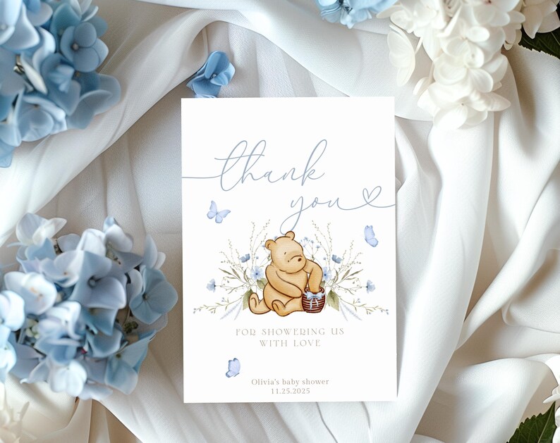 Pu&ograve; includere: Un biglietto di ringraziamento con un'illustrazione ad acquerello di Winnie the Pooh che tiene un barattolo di miele. La carta &egrave; decorata con farfalle e fiori blu e il testo "Grazie per averci riempito d'amore. Baby shower di Olivia 11.25.2015."