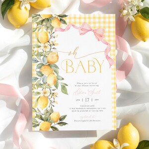 Op de afbeelding: Een uitnodiging voor een babyshower met een citroenthema. De uitnodiging bevat de woorden "oh BABY" in gouden letters, met een gele ruitjesrand en een roze lint. Citroenen en bloemaccenten versieren de uitnodiging.
