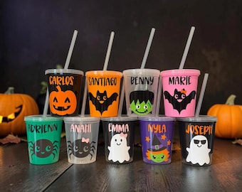 Peut inclure: Neuf gobelets en plastique transparent avec couvercles et pailles, chacun orné d'un motif d'Halloween unique et d'un prénom personnalisé. Les designs incluent une citrouille, des chauves-souris, Frankenstein, un fantôme, une araignée et une sorcière.