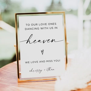 Könnte beinhalten: Ein goldfarbener Rahmen mit einem weißen Hintergrund und schwarzem Text. Das Schild lautet "To our love ones dancing with us in heaven ♡ We love and miss you! Chrissy + Ethan".