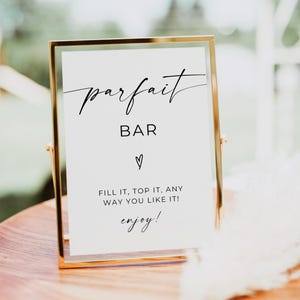 May include: A gold-framed sign with the word "parfait" in elegant script. Below, the word "BAR" is centered, followed by a heart symbol. The text "FILL IT, TOP IT, ANY WAY YOU LIKE IT! enjoy!" is also displayed.