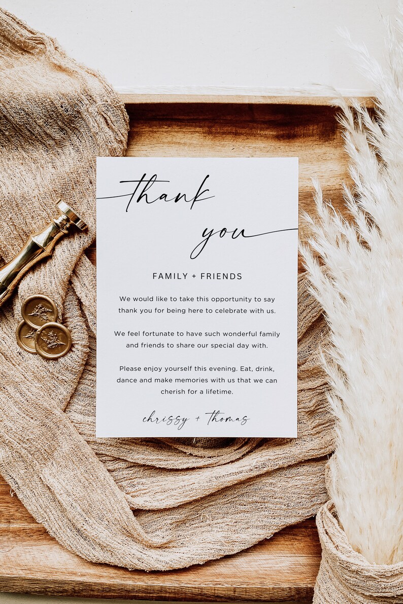 Puede incluir: Una tarjeta blanca con texto negro que dice "Gracias" en cursiva. La tarjeta tambi&eacute;n dice "Familia + Amigos" e incluye un mensaje agradeciendo a los invitados por asistir a la boda y celebrar con la pareja. La tarjeta est&aacute; firmada "chrissy + Thomas".
