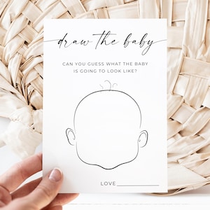 May include: A white card with the text "draw the baby" in cursive script. Below, it reads "CAN YOU GUESS WHAT THE BABY IS GOING TO LOOK LIKE?" A line drawing of a baby's face is in the center. The word "LOVE" is at the bottom.